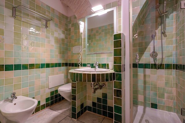 A bathroom with a sink, toilet, bidet, and shower.