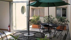 A patio with two green umbrellas, a round table, and chairs. - Albergo Meublè Abatjour (Mantua)