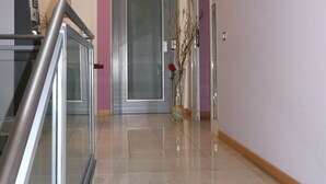 A hallway with a glass door, a staircase, and a vase with a red flower. - Albergo Meublè Abatjour (Mantua)