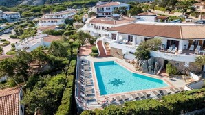 Un resort con una gran piscina rodeada de sillas reclinables y montañas al fondo.