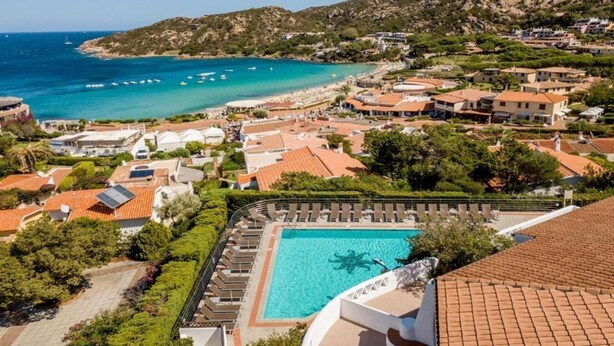 Un resort costero con piscina, casas escalonadas y vistas al mar.