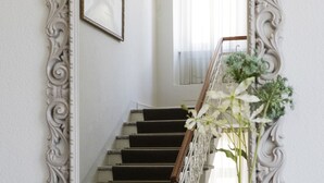 Un espejo con un marco decorativo, un jarrón con flores y una cesta de frutas.