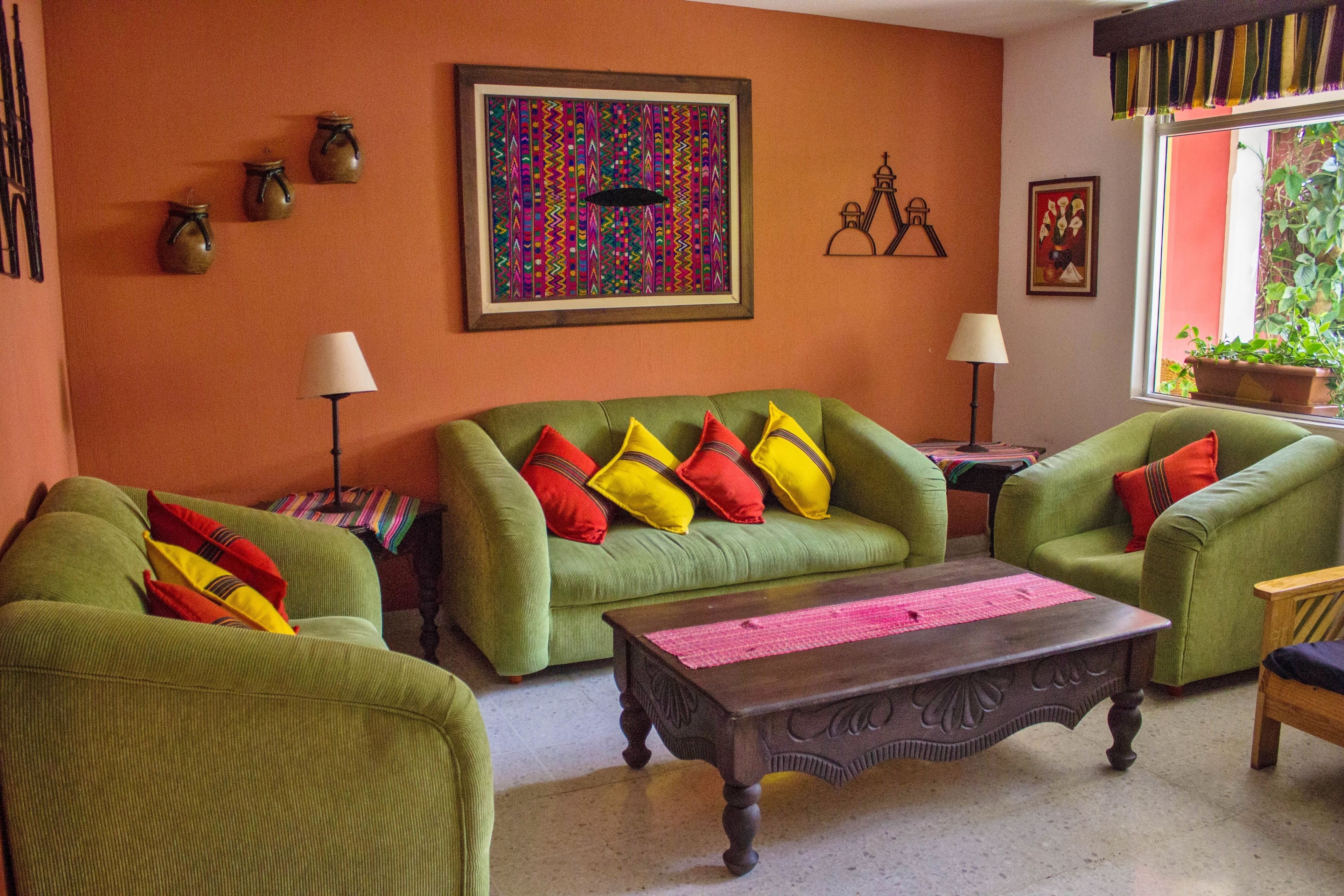 A living room with green sofas, colorful cushions, a wooden coffee table, and a large framed artwork on the wall.