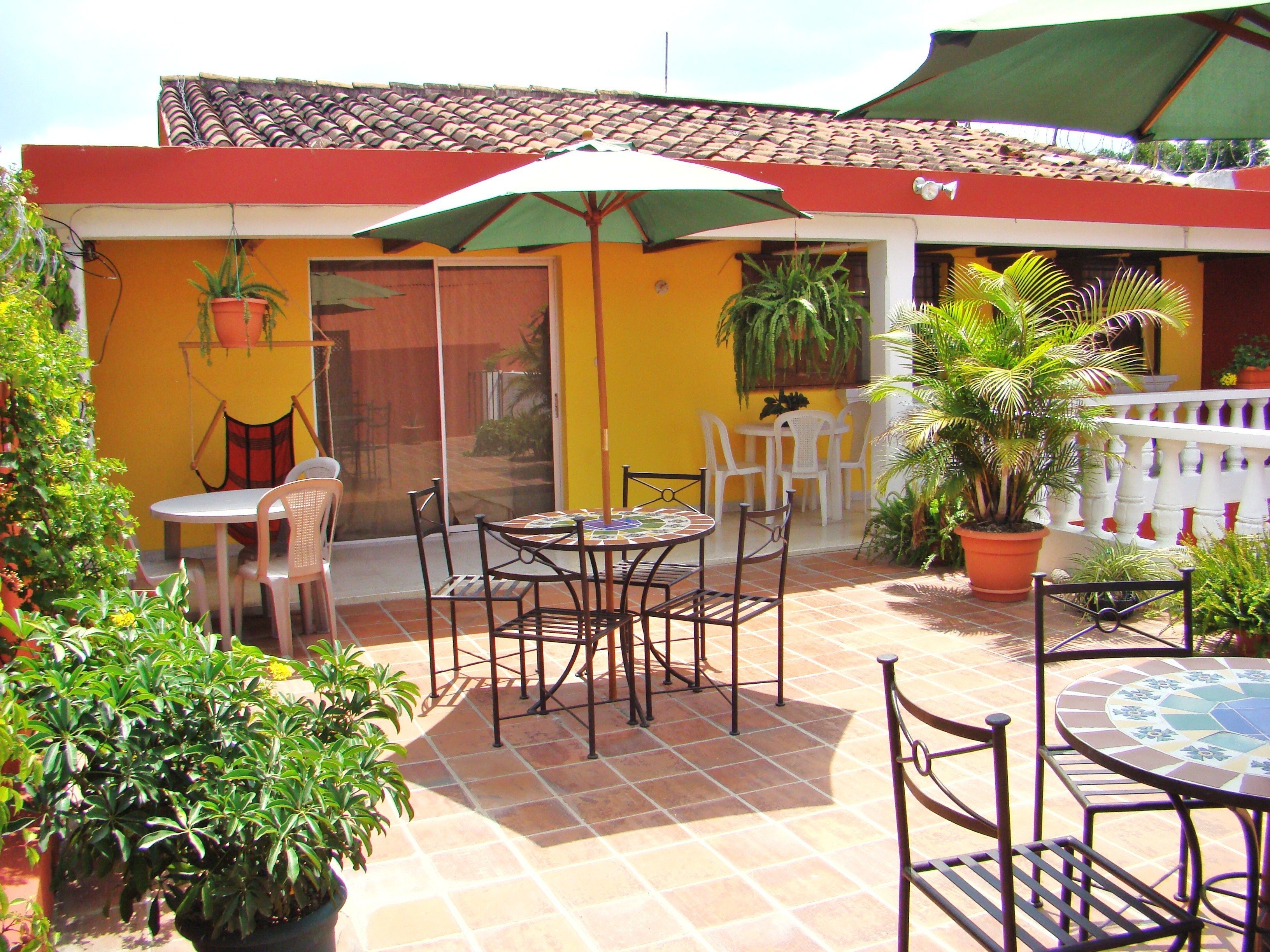 Eine Terrasse im Freien mit Fliesenboden, einem Tisch mit Stühlen und Blumentöpfen.
