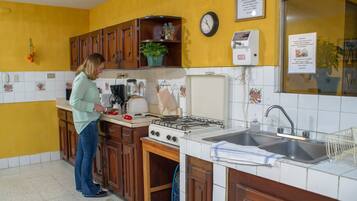 A kitchen with wooden cabinets, a stove, a sink, and a clock on the wall.