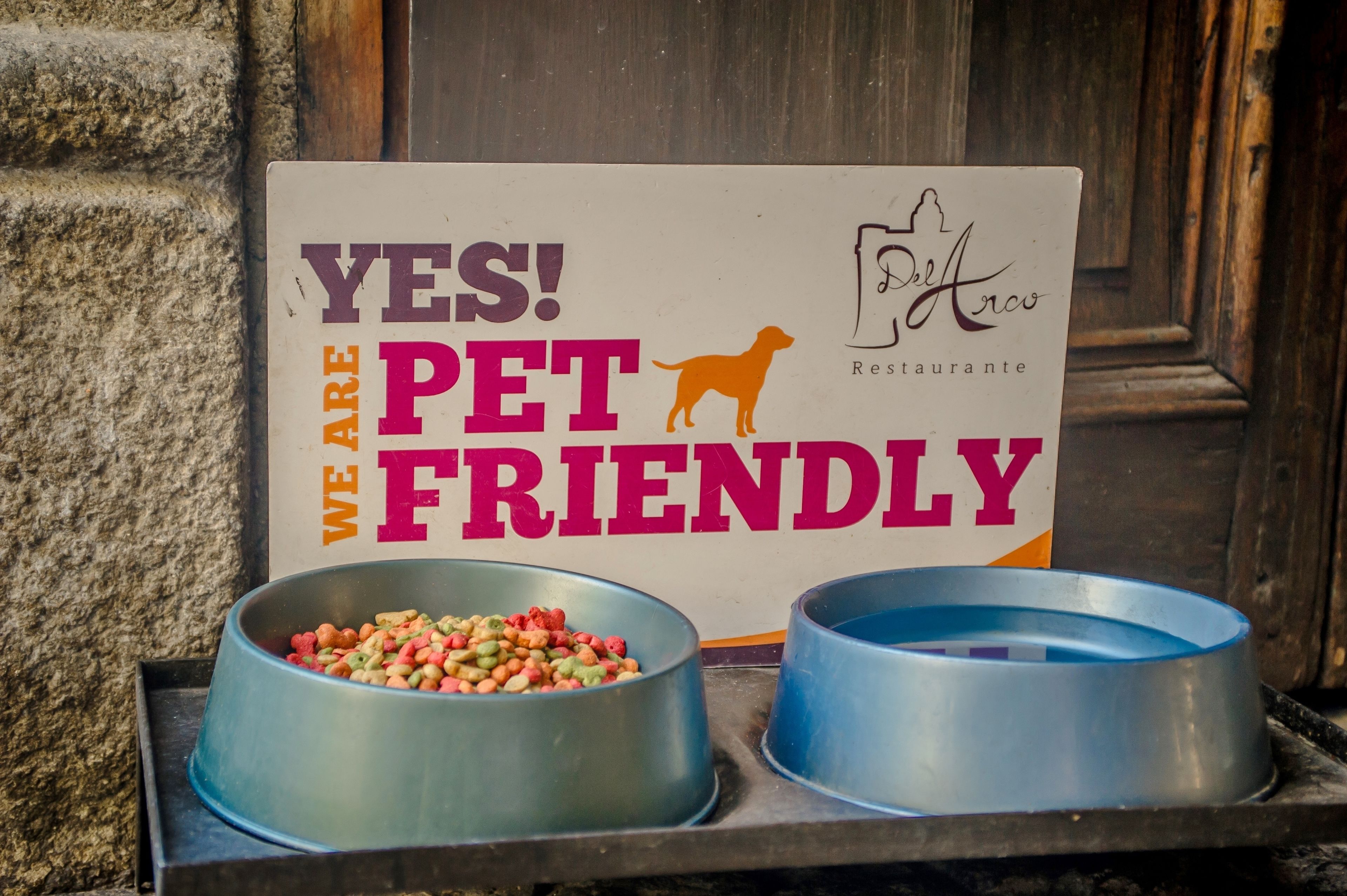 A sign that reads "YES! WE ARE PET FRIENDLY" with two pet bowls in front.