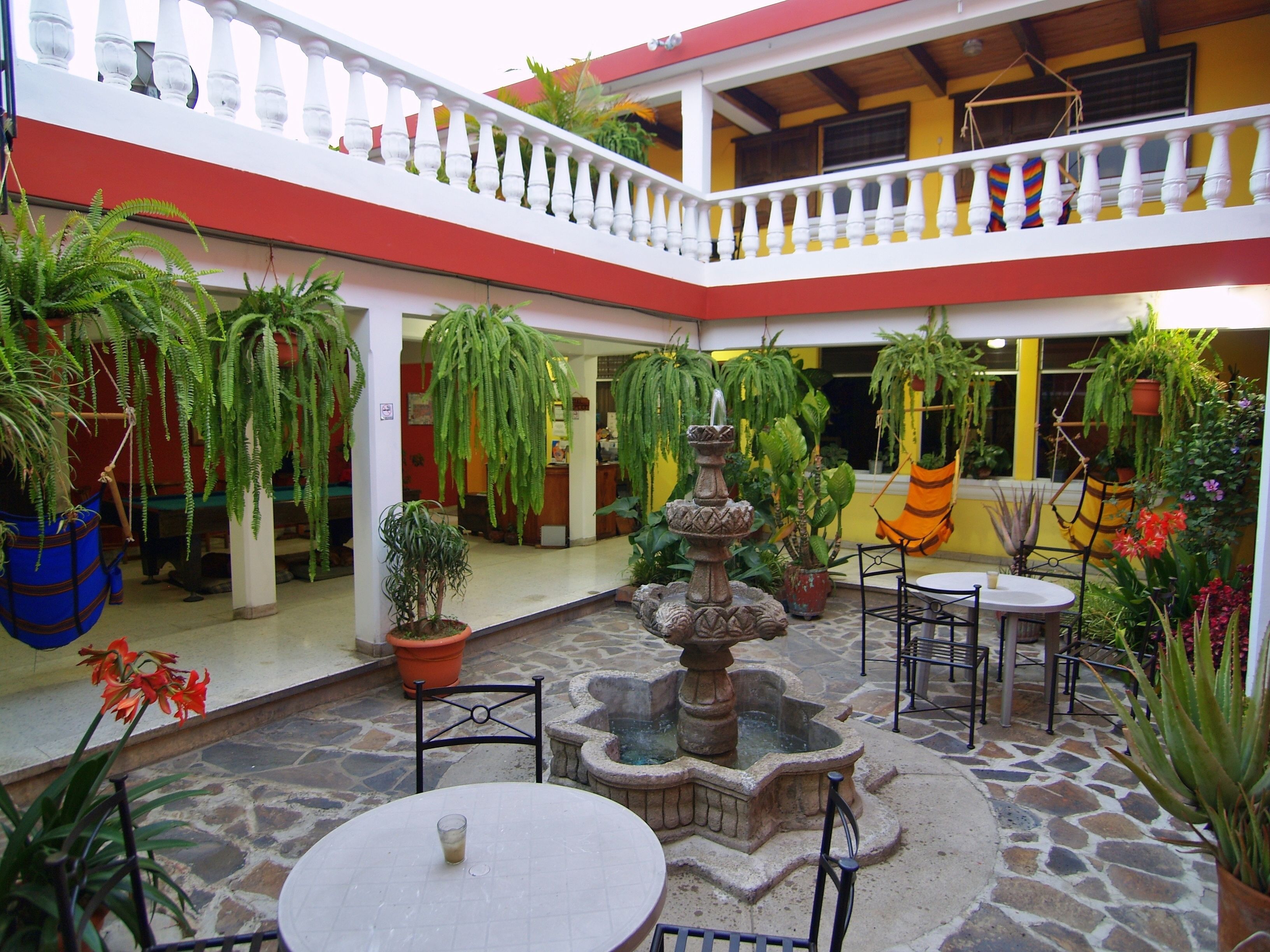 A courtyard with a fountain, potted plants, and outdoor seating.