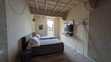 Ein Schlafzimmer mit zwei Betten, einem an der Wand befestigten Fernseher und einem Balkon mit Aussicht.