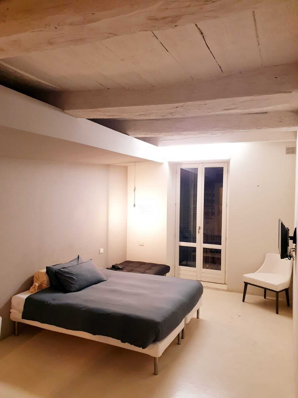 Ein Schlafzimmer mit einem Bett, einem Sessel, einem Fernseher und einem Fenster.