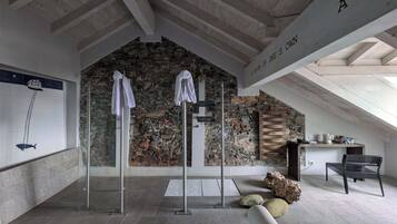 A modern interior with a stone wall, a glass shower enclosure, and a bench with a stone sculpture.