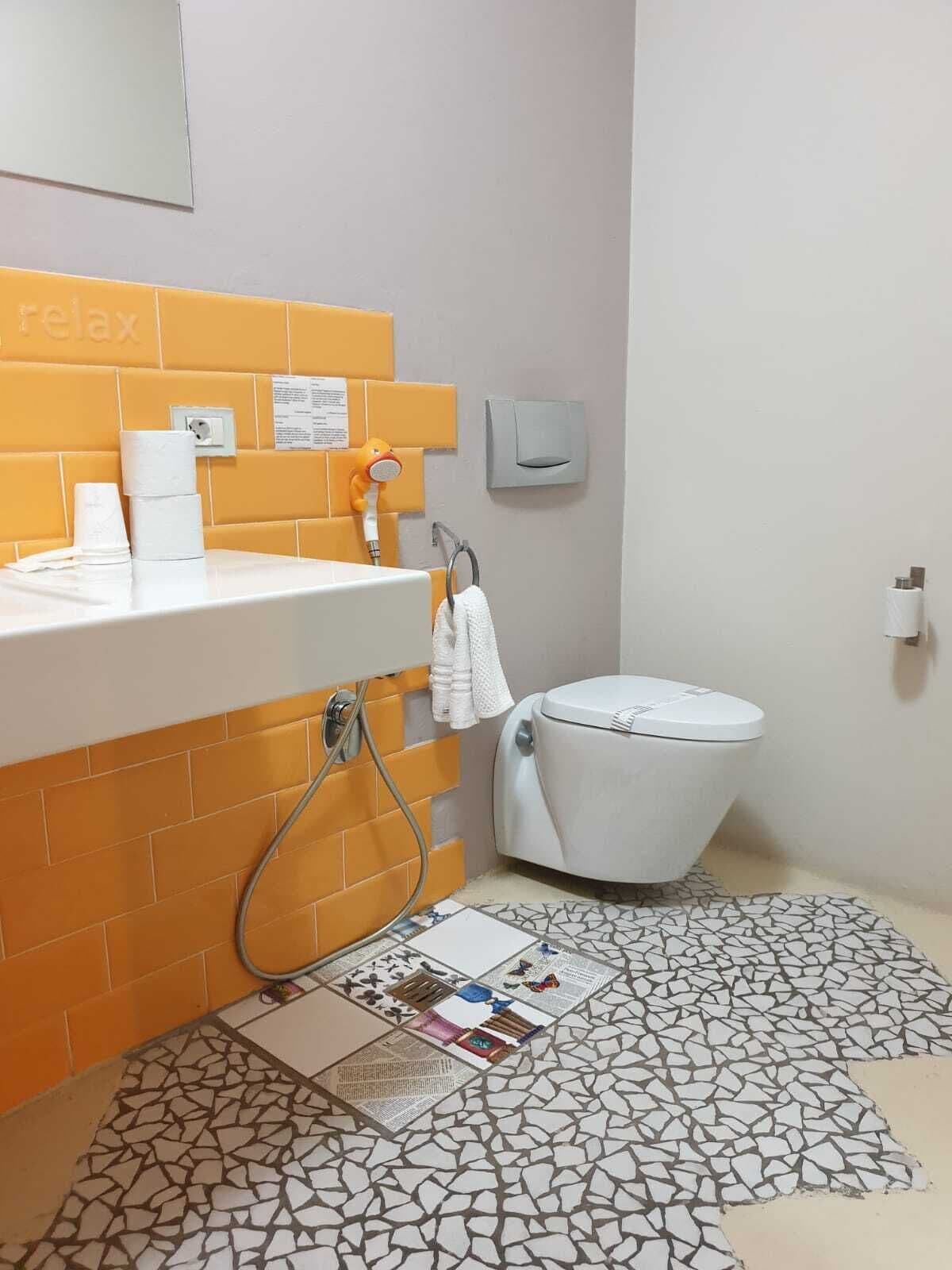 A bathroom with a white toilet, a sink with a towel rack, and a shower area.