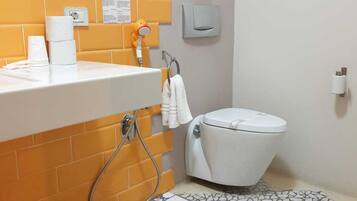 A bathroom with a white toilet, a sink with a towel rack, and a shower area.