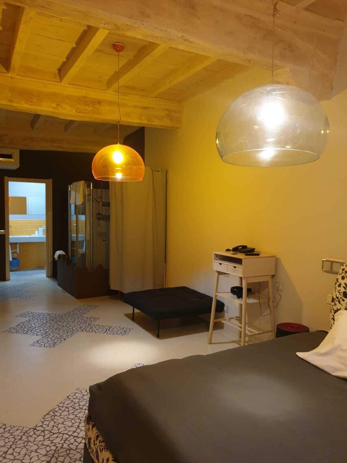 Un dormitorio con cama, mesita de noche y lámpara colgante.