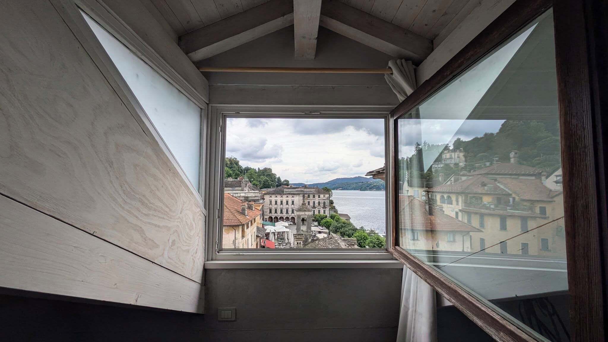 Una habitación con un amplio ventanal que ofrece vistas a un pueblo histórico a orillas de un lago.
