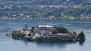 Une ville située au bord d’un lac, avec un bâtiment imposant doté d’une tour, entouré de maisons plus petites et d’une végétation luxuriante.