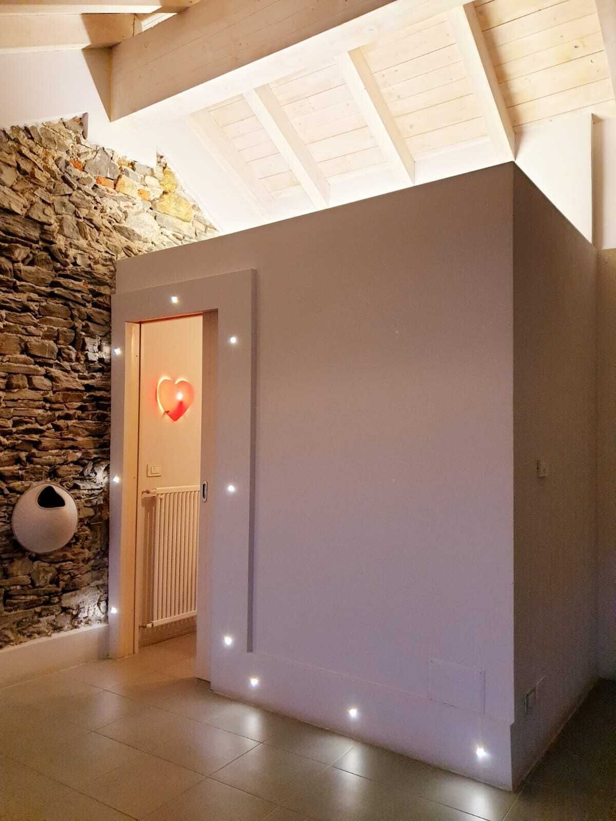 A modern interior with a stone wall, a heart-shaped light, and a door with recessed lighting.