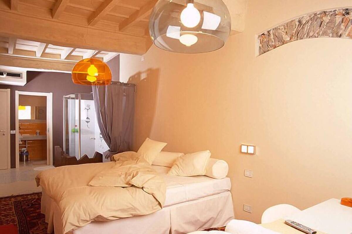 A bedroom with a bed, a bedside table, a remote control, and a large window.