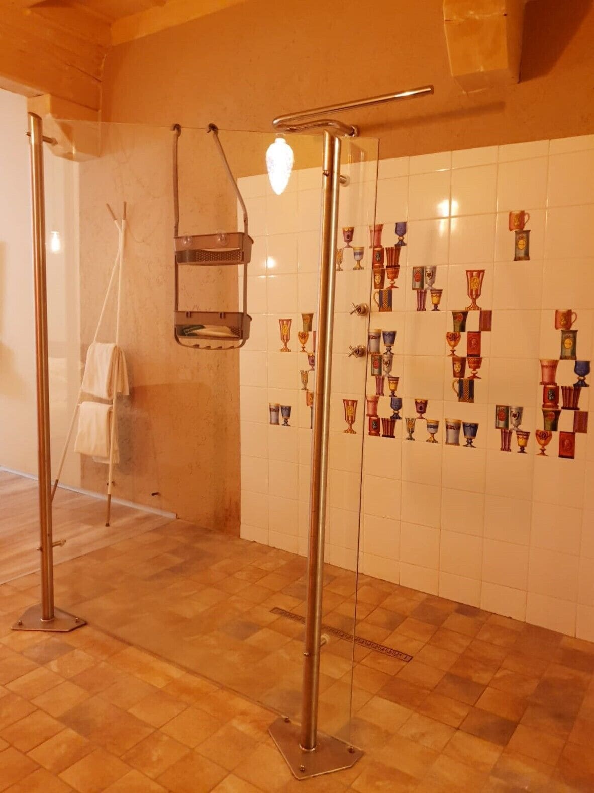 Un baño con pared de azulejos que muestra una fila de trofeos, piso de madera y un perchero para toallas.