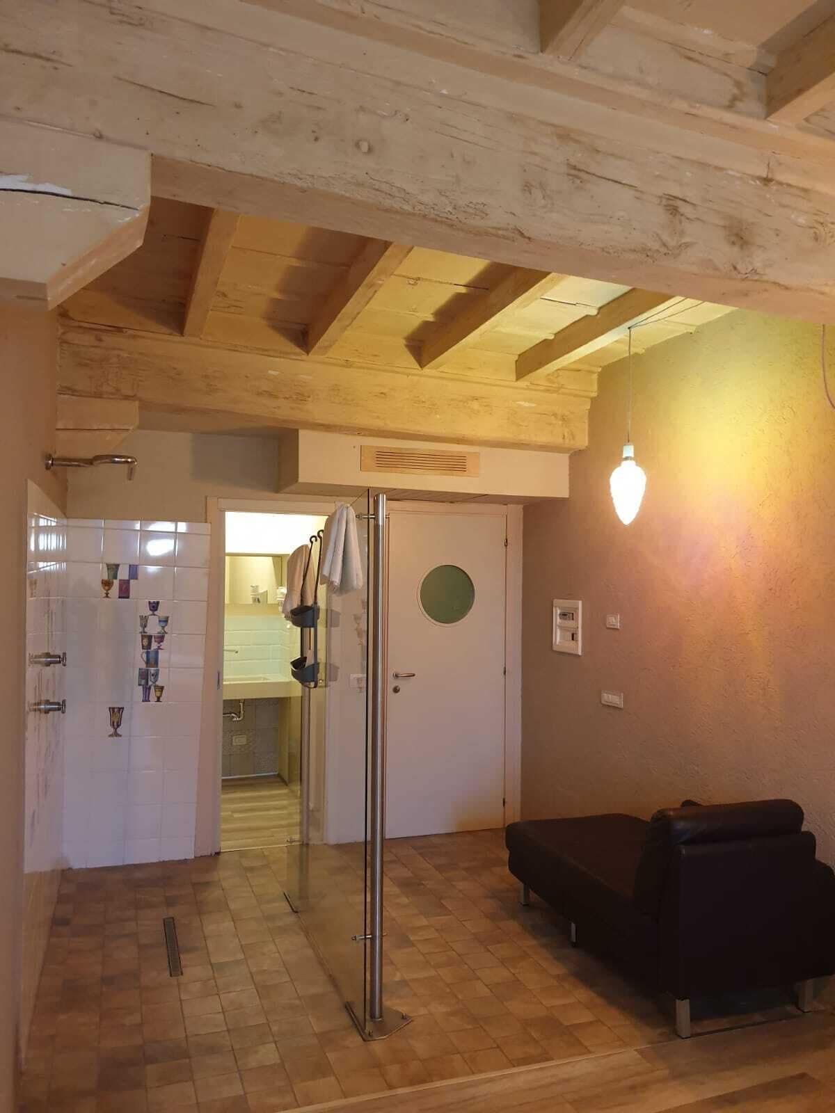 Una habitación con vigas de madera, un refrigerador, un lavamanos y un sofá.