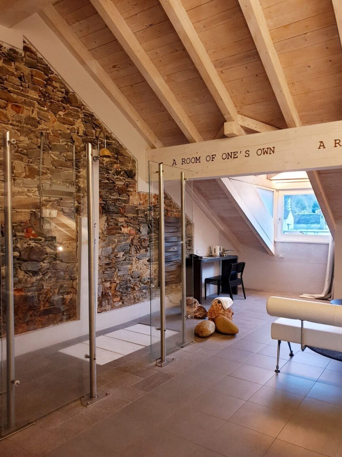 A room with a stone wall, wooden beams, and a sign reading "A ROOM OF ONE'S OWN".