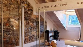 A room with a stone wall, wooden beams, and a sign reading "A ROOM OF ONE'S OWN".