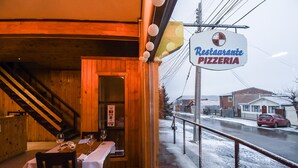 A restaurant with a sign reading "Restaurante Pizzeria" and a view of a snowy street outside. - Hostal Alcazar  (Natales)