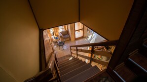 A wooden staircase leading to a room with a sofa and a table. - Hostal Alcazar  (Natales)