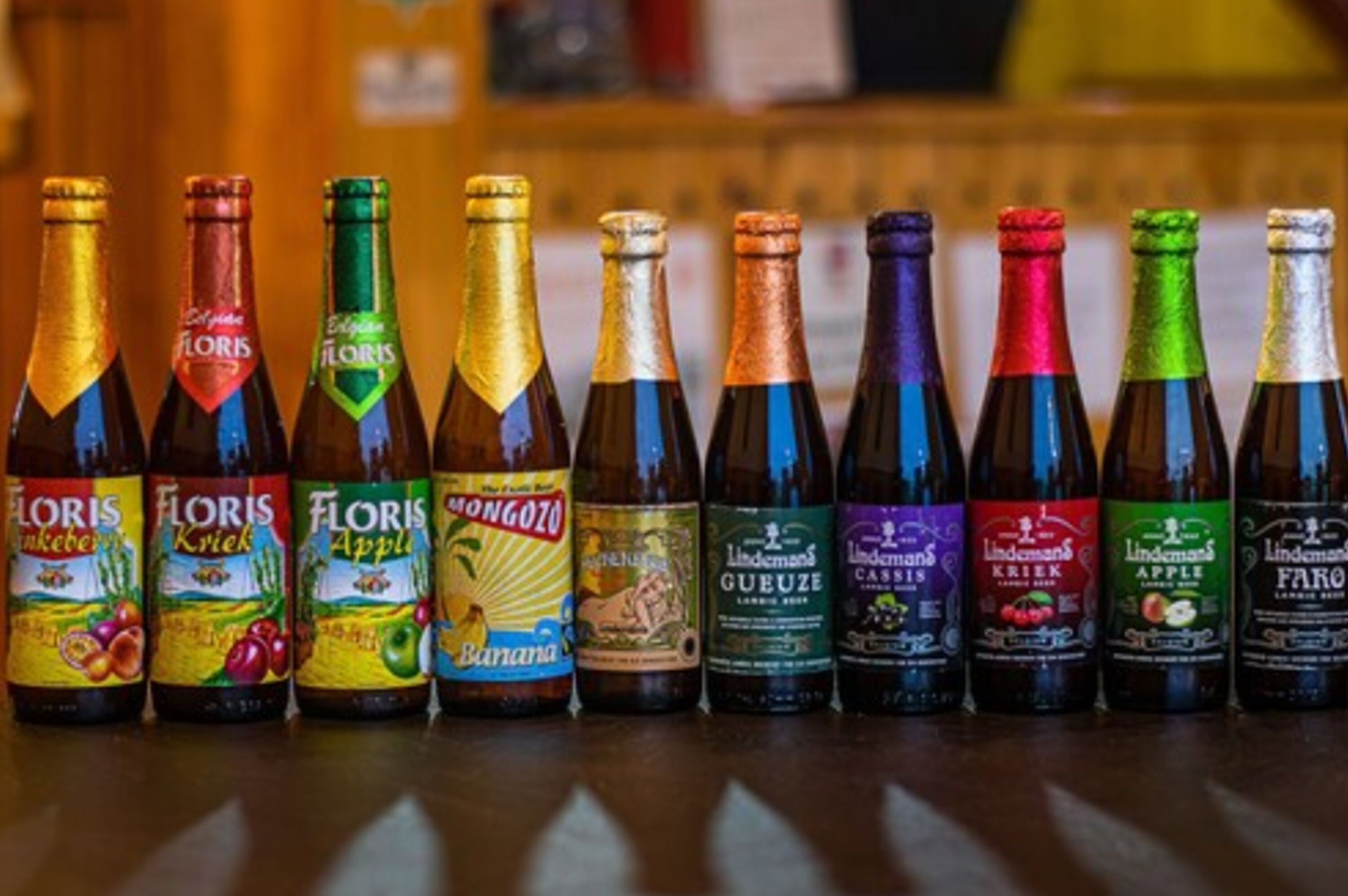 A row of beer bottles with labels such as "Floris," "Mongozoo," and "Lindemans."