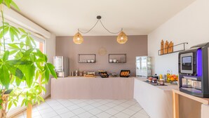 Een moderne keuken met een centraal eiland, hanglampen, een koelkast en een koffiezetapparaat.