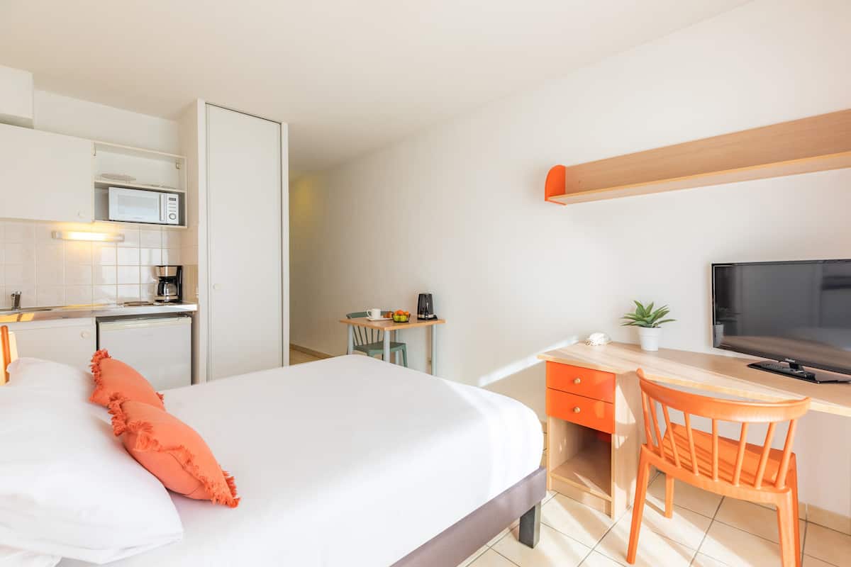 Een hotelkamer met een bed, een bureau, een stoel, een televisie, een magnetron en een koffiezetapparaat.