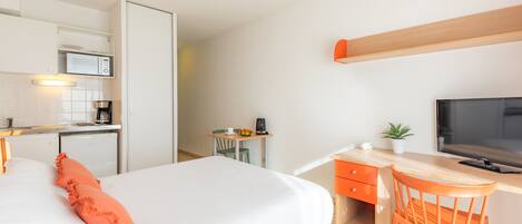 A hotel room with a bed, a desk, a chair, a television, a microwave, and a coffee maker.