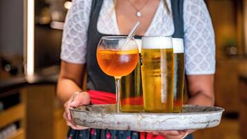 Eine Person hält ein Tablett mit einem Glas bernsteinfarbenen Getränks und zwei Biergläsern.