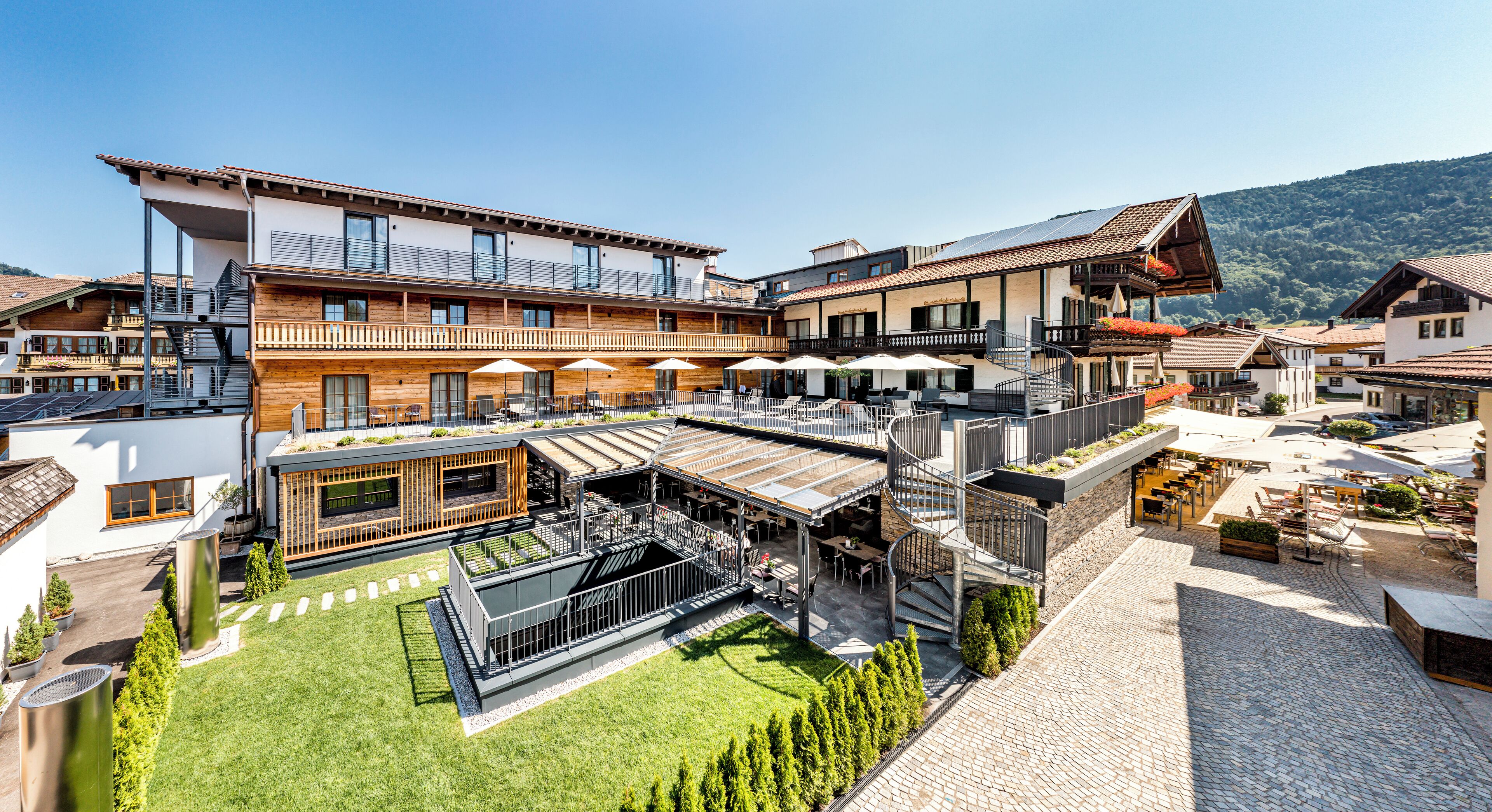 A modern hotel with multiple balconies, outdoor seating areas, and a central courtyard.