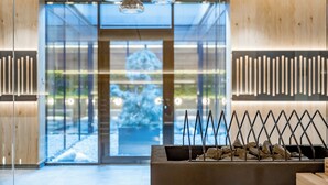 A modern lobby with a glass entrance, wooden accents, and a central water feature. - Ruhpoldinger Hof (Ruhpolding)