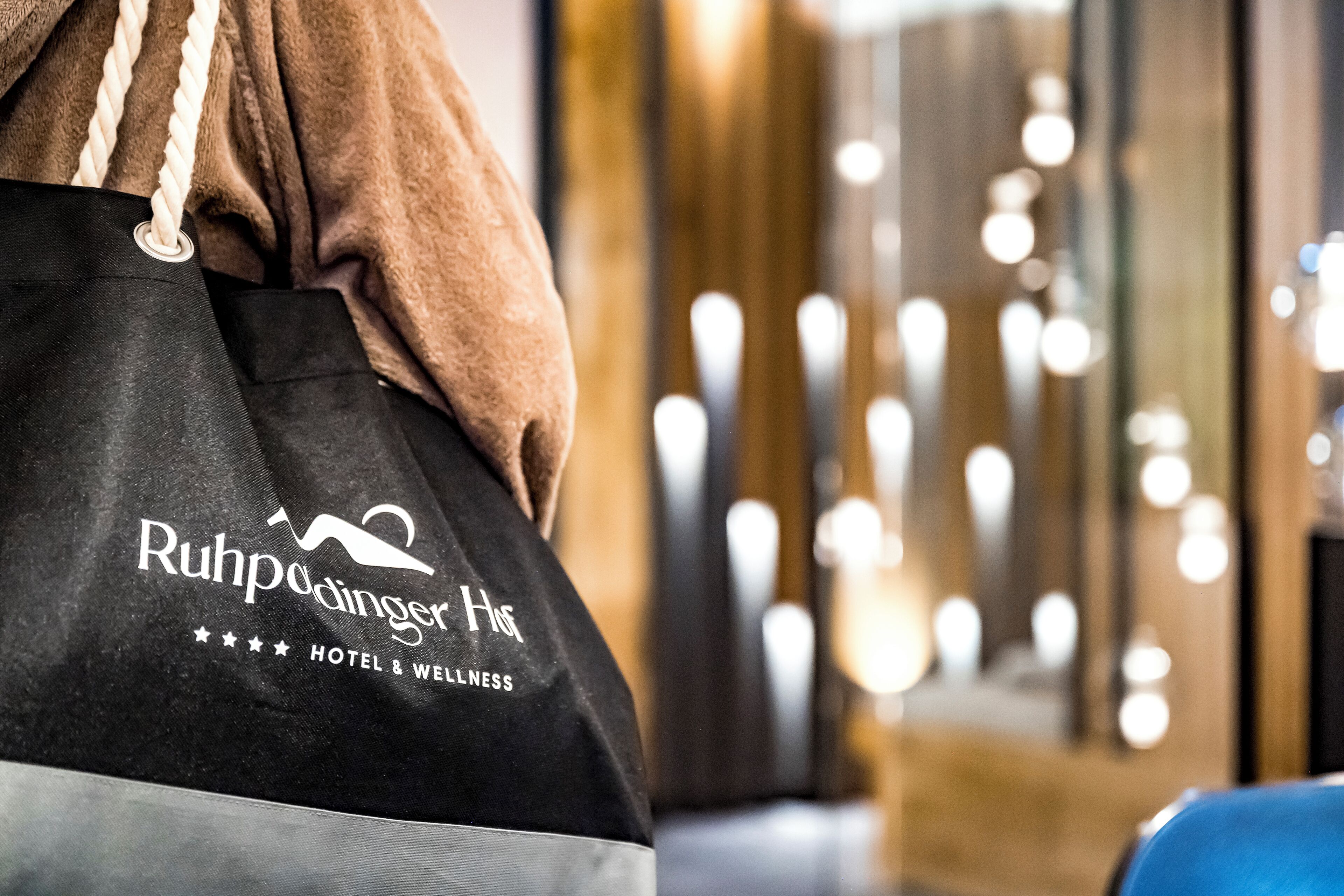Una bolsa de hotel negra con el logotipo y el nombre "Ruhpolding Hotel" y el eslogan "HOTEL & WELLNESS".