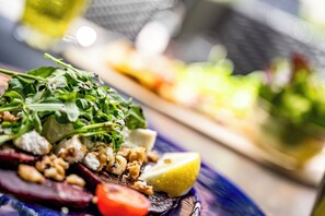 A close-up of a salad with greens, nuts, and a lemon wedge.
