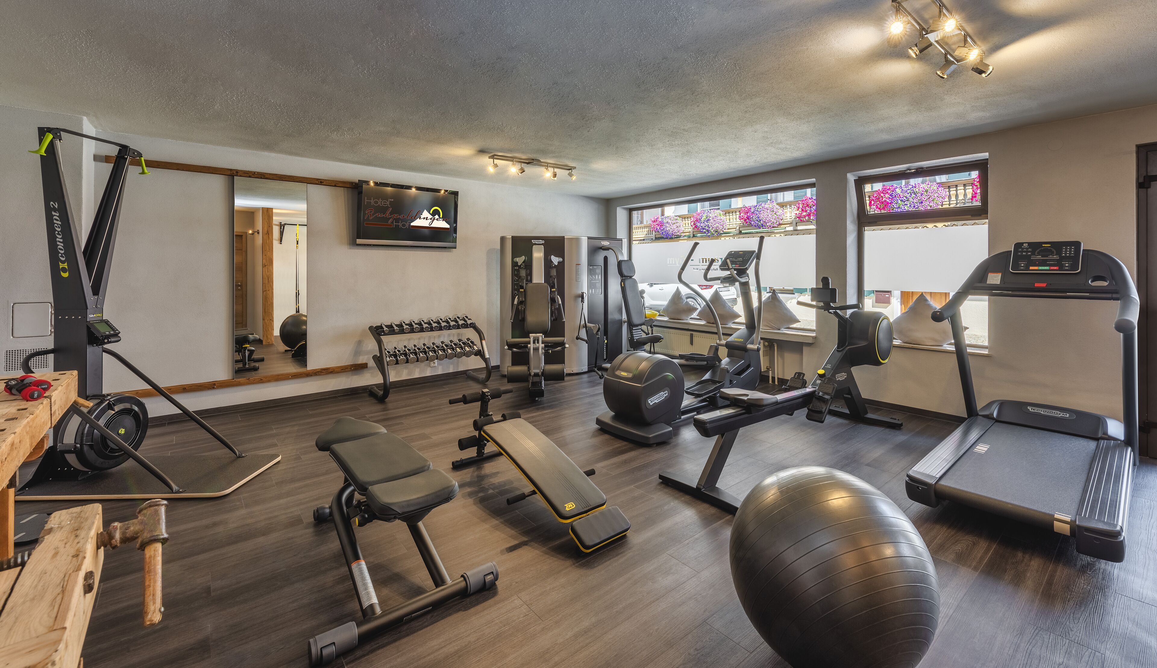 Un gimnasio con equipo de ejercicio, una banca, una máquina de remo y una cinta de correr.