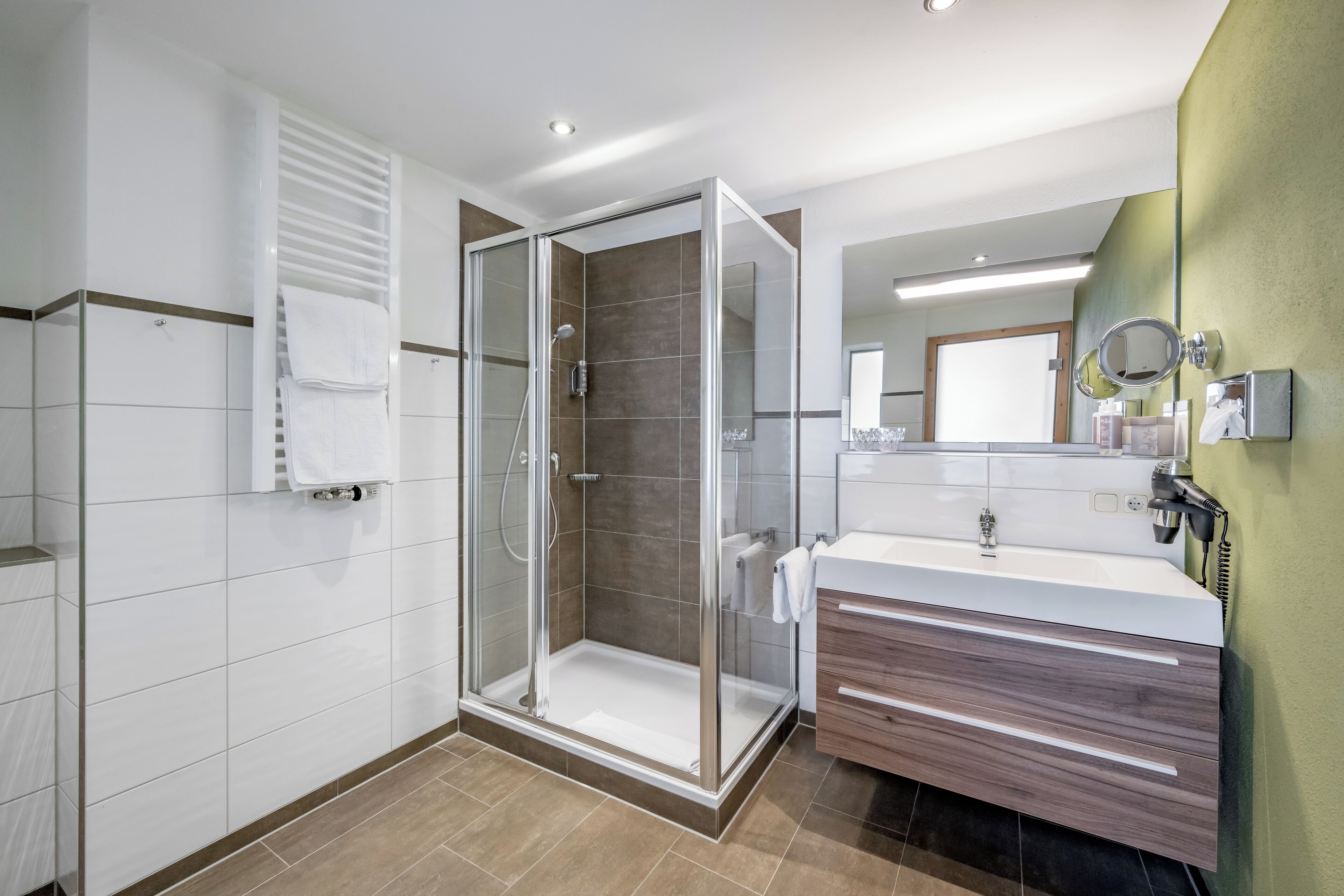 A modern bathroom with a glass-enclosed shower, a vanity with a mirror, and a towel rack.