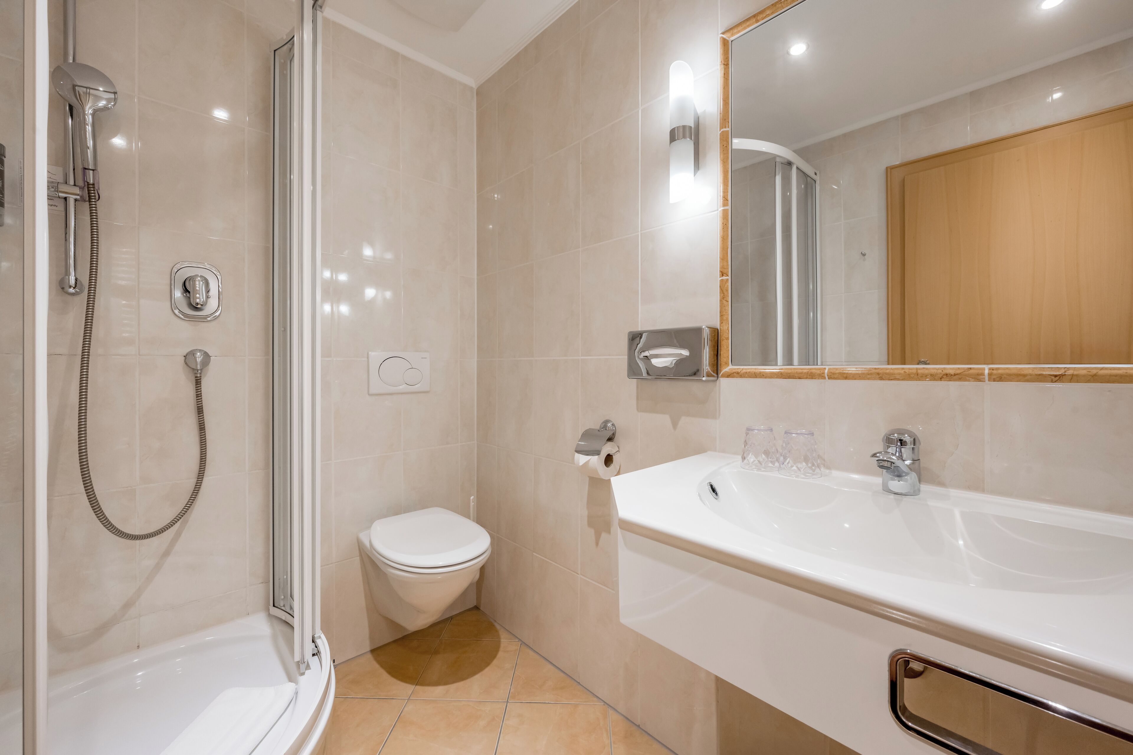 A modern bathroom with a glass-enclosed shower, a white toilet, and a large sink with a mirror.