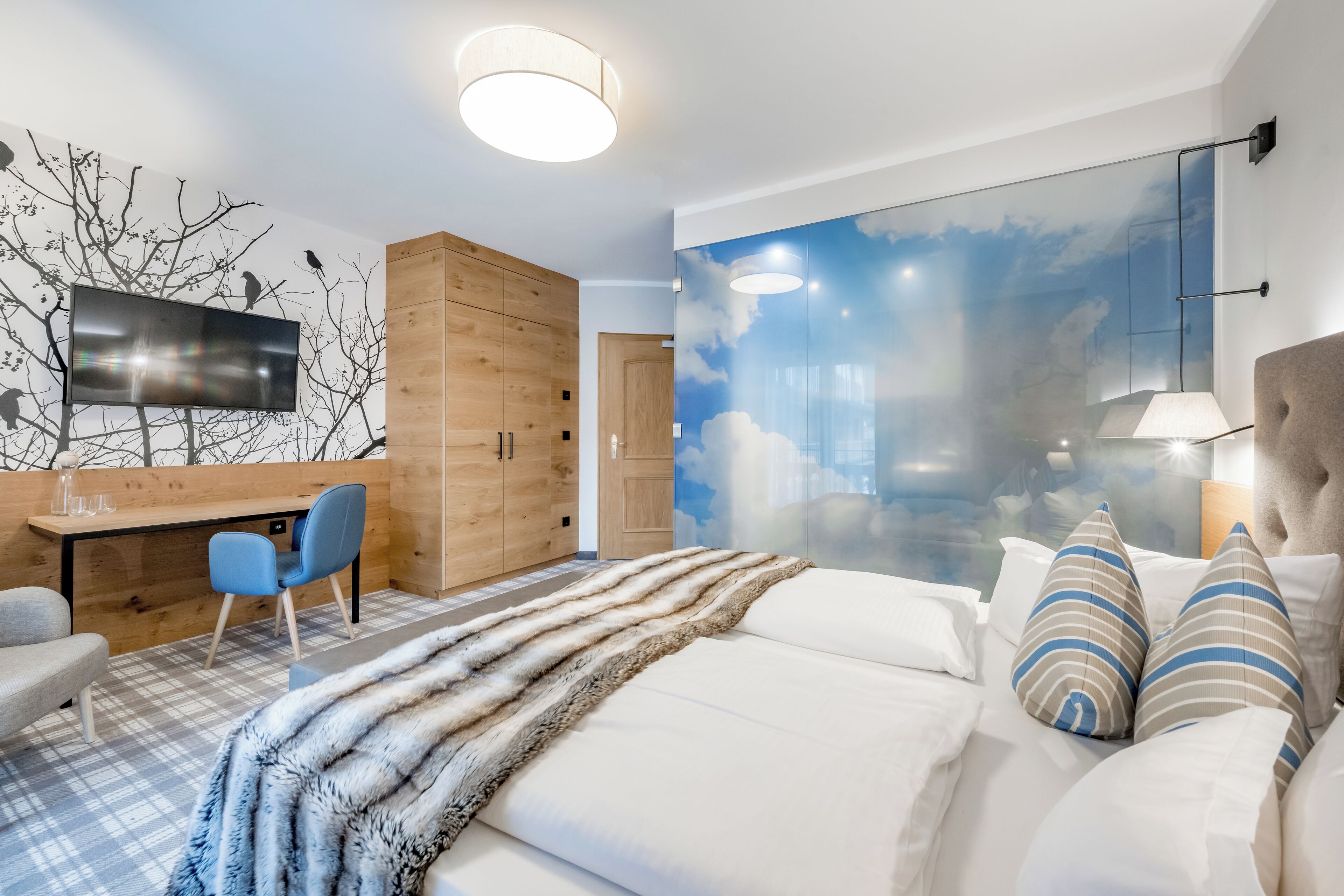 A modern bedroom with a bed, a desk, and a chair.