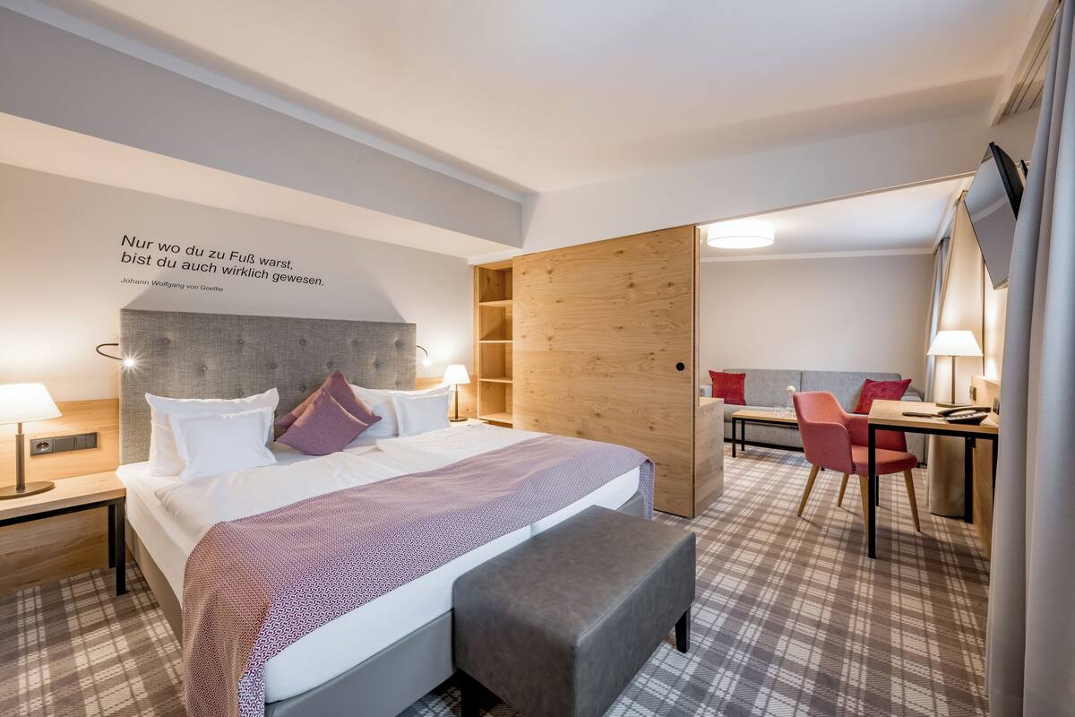 A hotel room with a bed, bedside tables, a desk, and a chair.