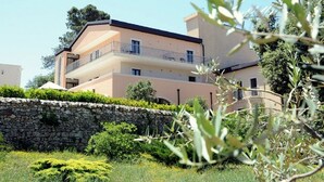 A multi-story residential building with balconies, surrounded by greenery and a stone wall. - Hotel Villa Rosa (Martina Franca)
