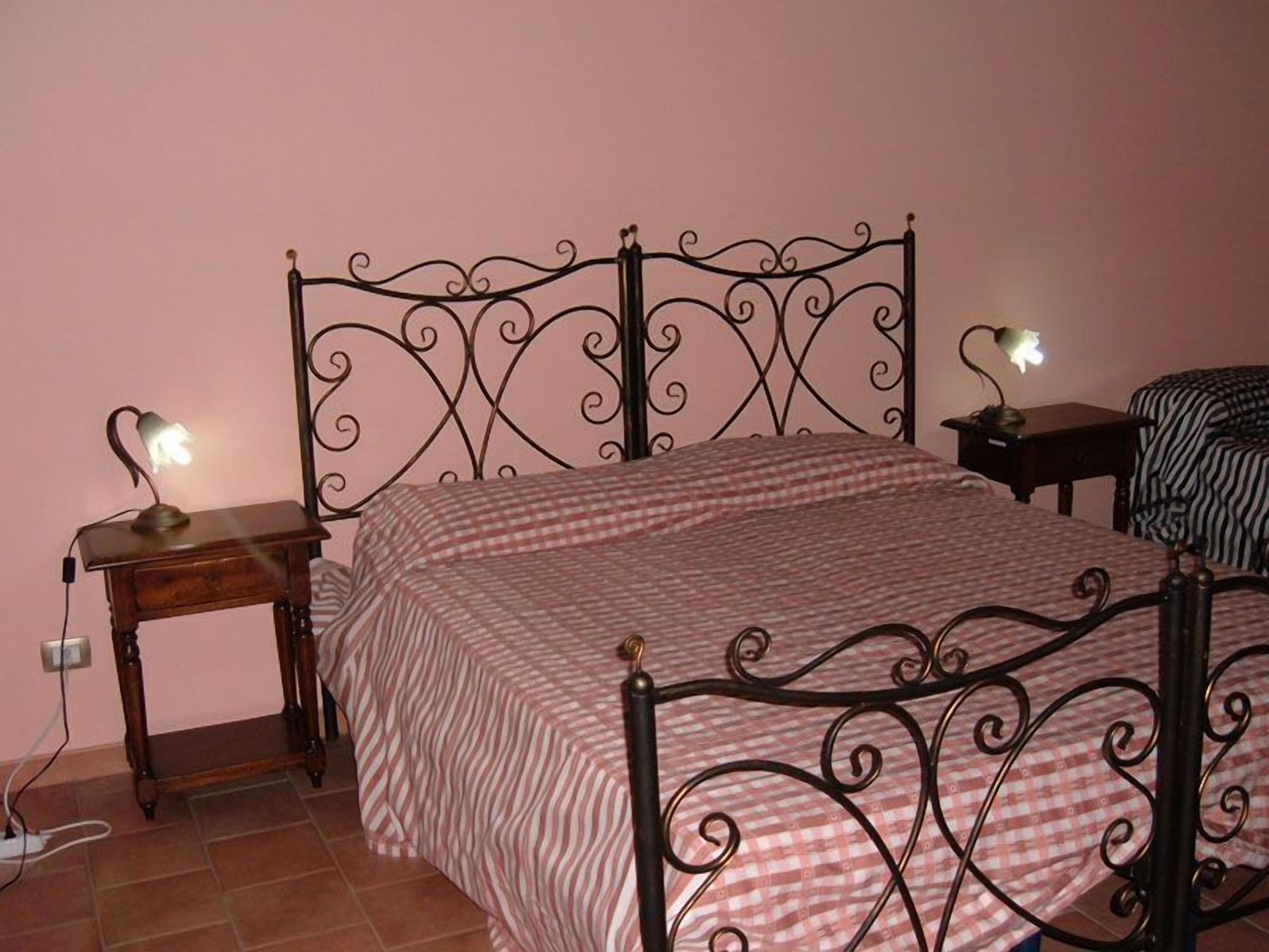 Ein Schlafzimmer mit einem Metallbettgestell, einer karierten Bettdecke, einem Nachttisch mit Lampe und einem Zebra-Muster-Sessel.