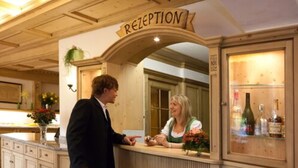 Ein Empfangsbereich mit Holztresen, einem Schild darüber und einer Vitrine mit Flaschen.