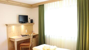 Ein Hotelzimmer mit einem Bett, einem Schreibtisch mit Computer, einem Sessel und einem Fernseher.