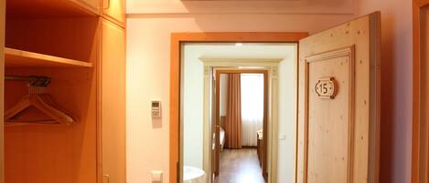 A hotel hallway with a wooden door marked "15", an air conditioning unit, and a coat rack.