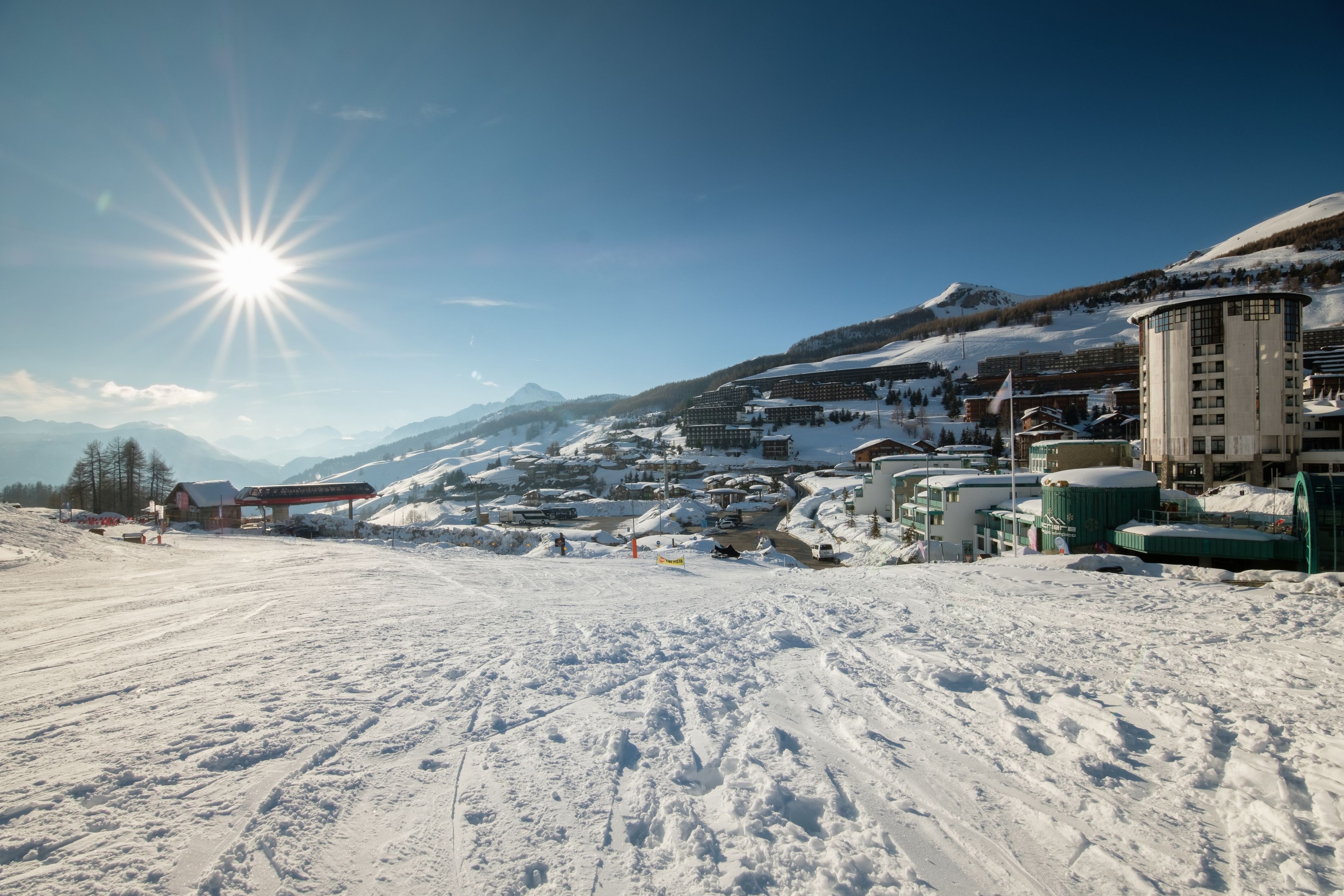 Ein schneebedecktes Skigebiet mit Gebäuden und blauem Himmel.