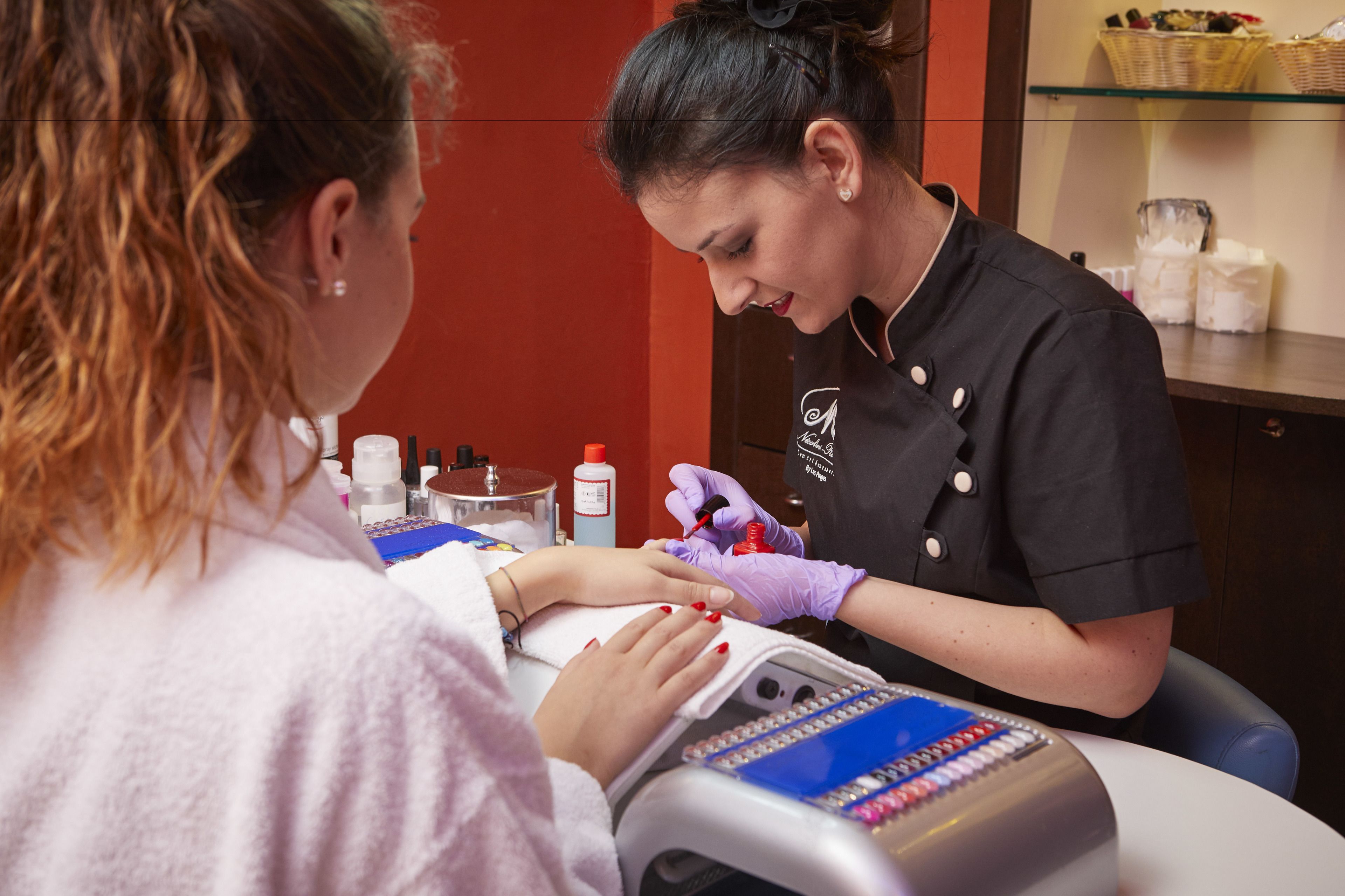 Ein Nagelstudio mit roter Wand und einer Theke mit verschiedenen Nagelprodukten.