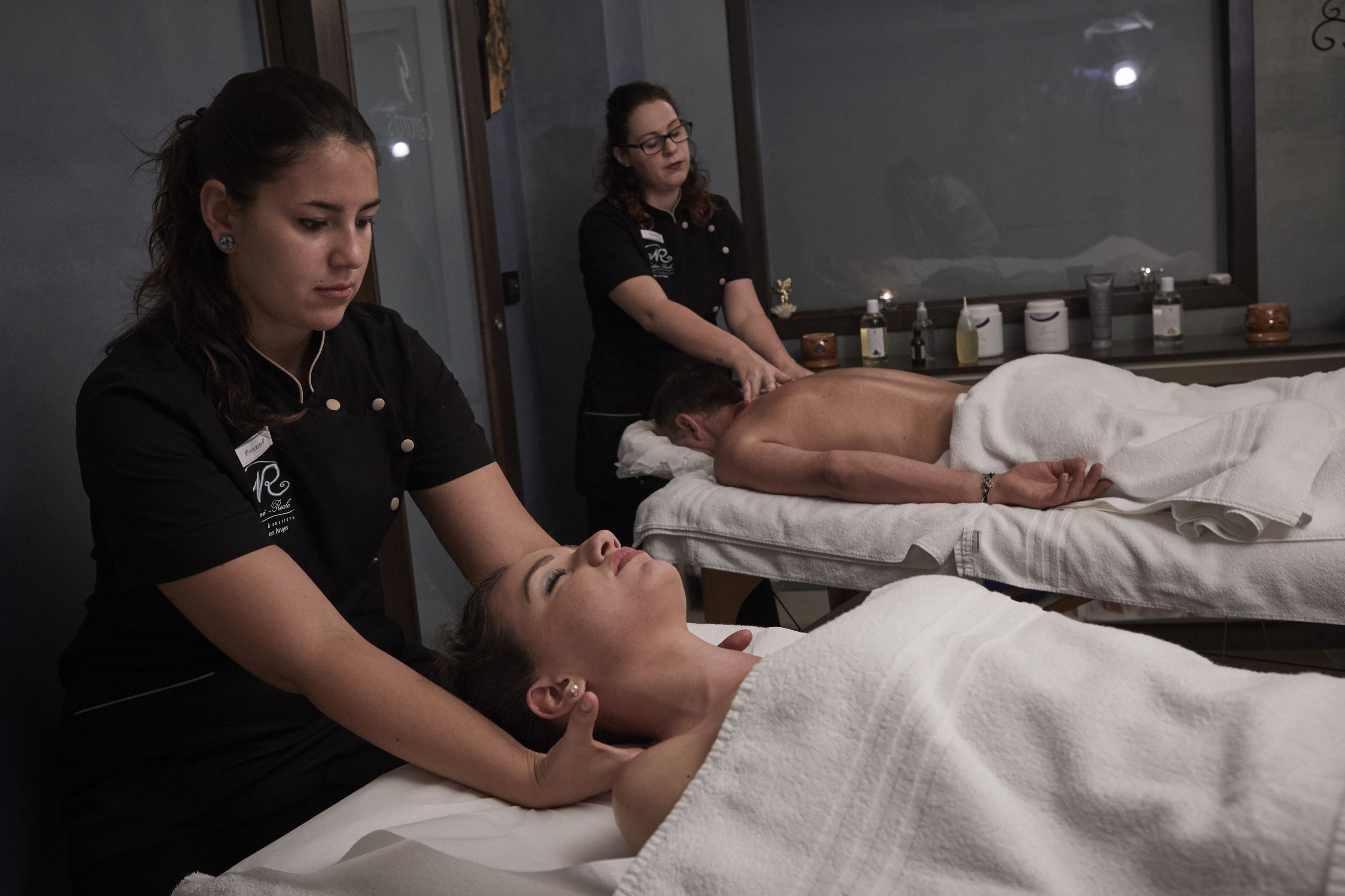 Un cuarto de terapia de masajes con dos clientes recibiendo tratamientos.