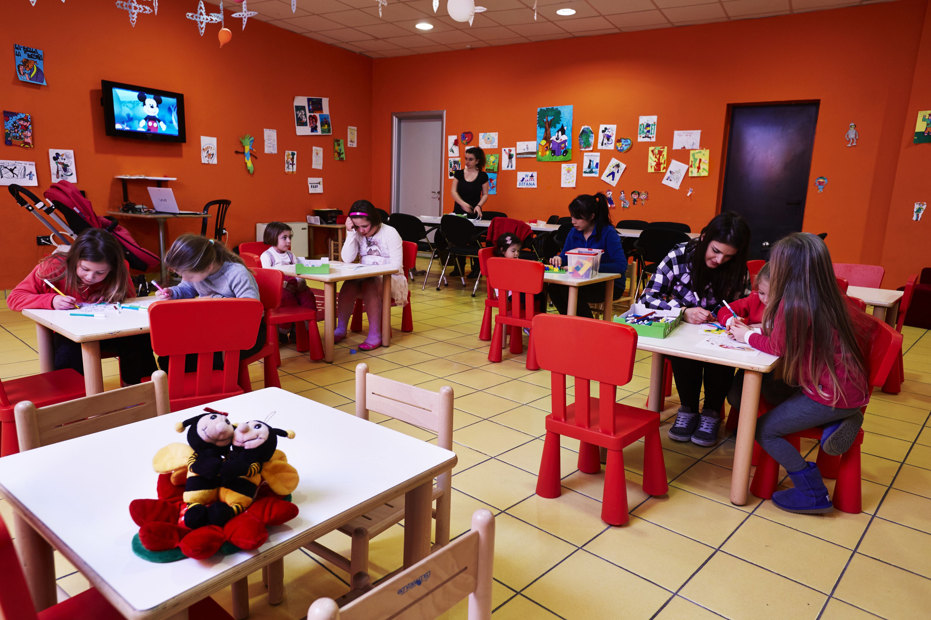 A classroom with children seated at tables, engaged in activities.